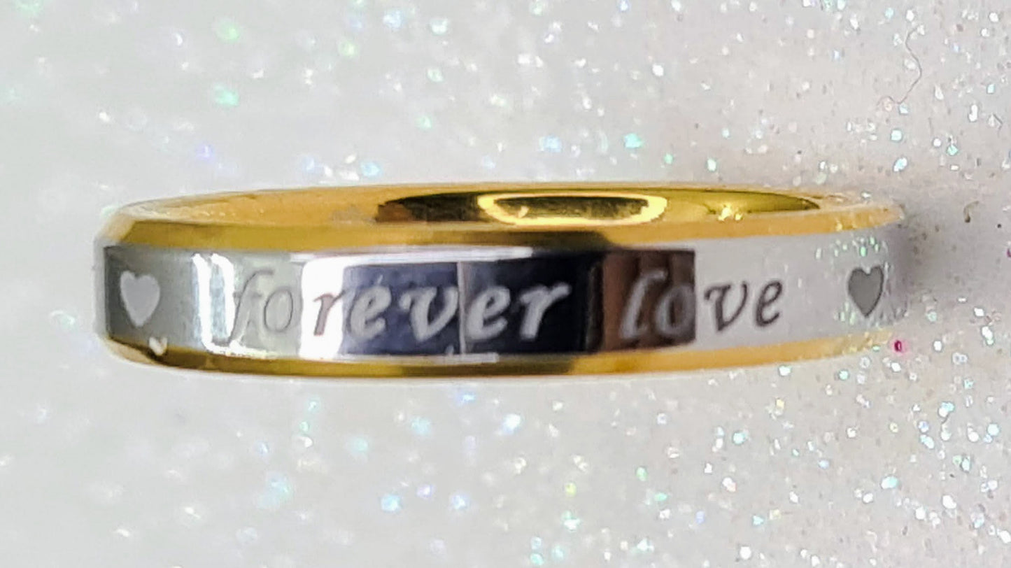Anillo "Forever Love" tipo alianza de matrimonio o pareja en acero inoxidable bicolor y ancho de 4mm. Se incluye grabado de nombres y fecha importante gratis. Posa sobre fondo brillante.