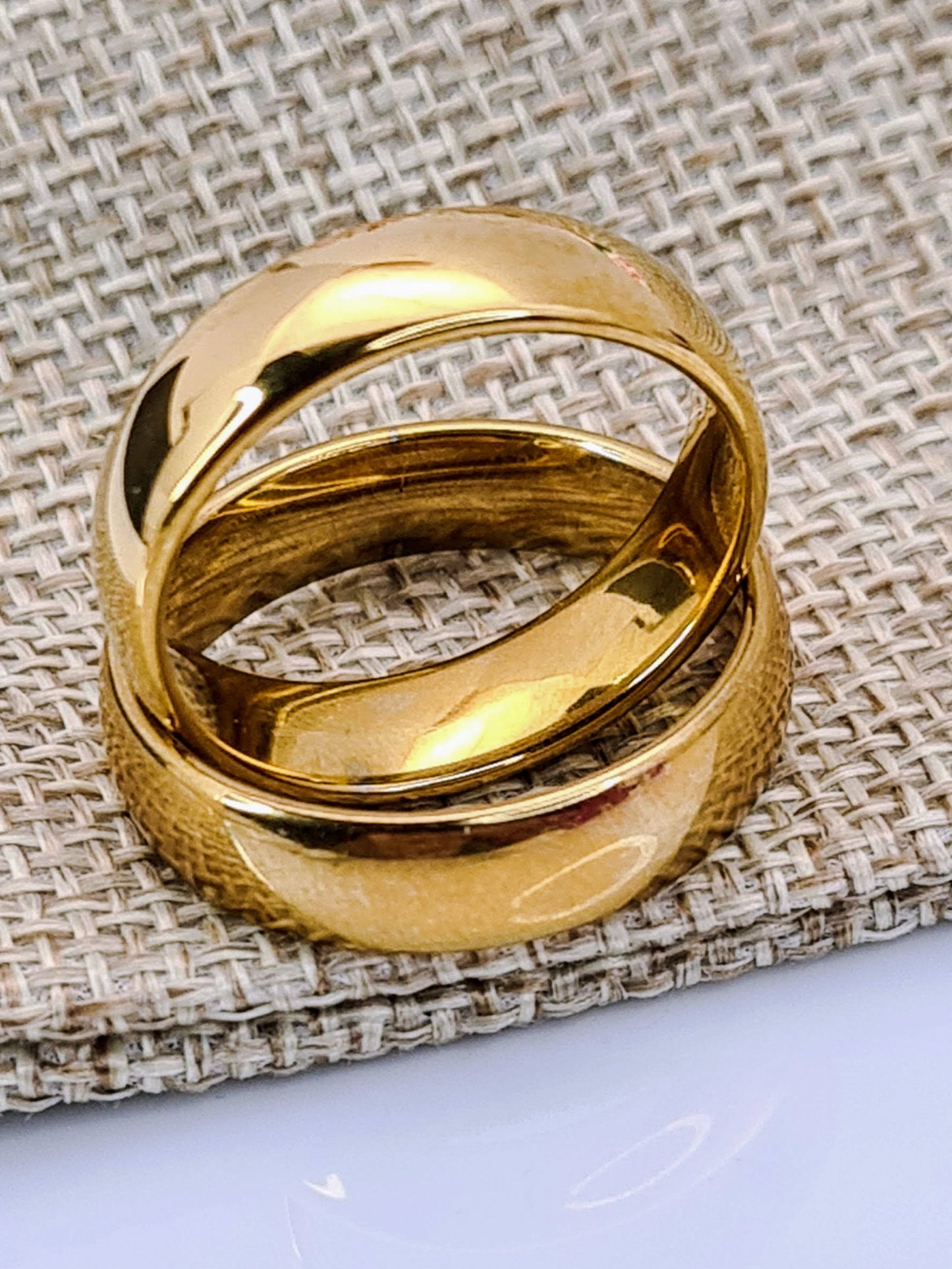 Par de Anillos tipo alianza de matrimonio o pareja en acero inoxidable en color dorado y ancho de 6mm sobre un saquito de arpillera. Se incluye grabado de nombres y fecha importante gratis.